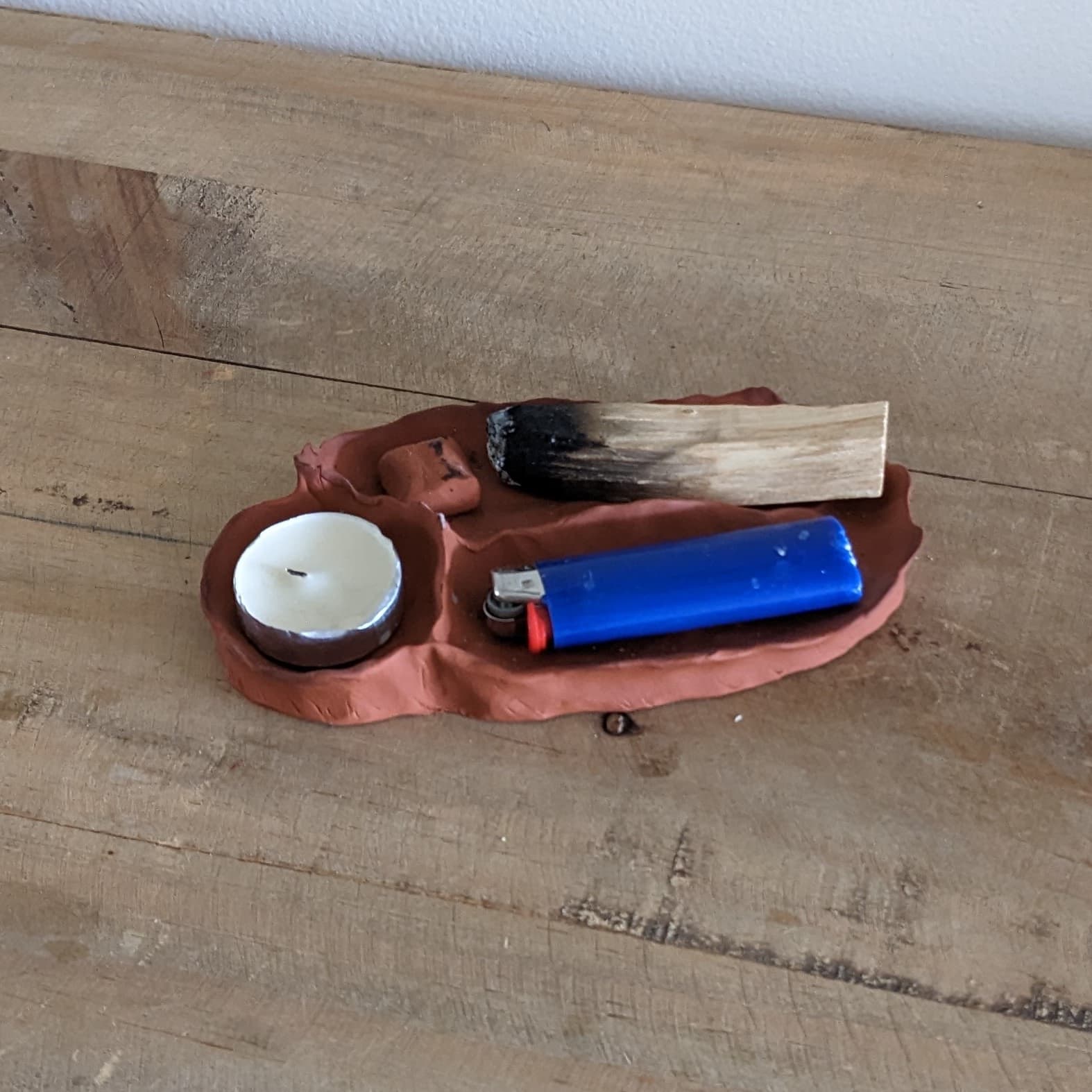 Palo Santo Holder made from oven-dry clay, designed to hold a tea light, a lighter, and a single piece of Palo Santo wood.